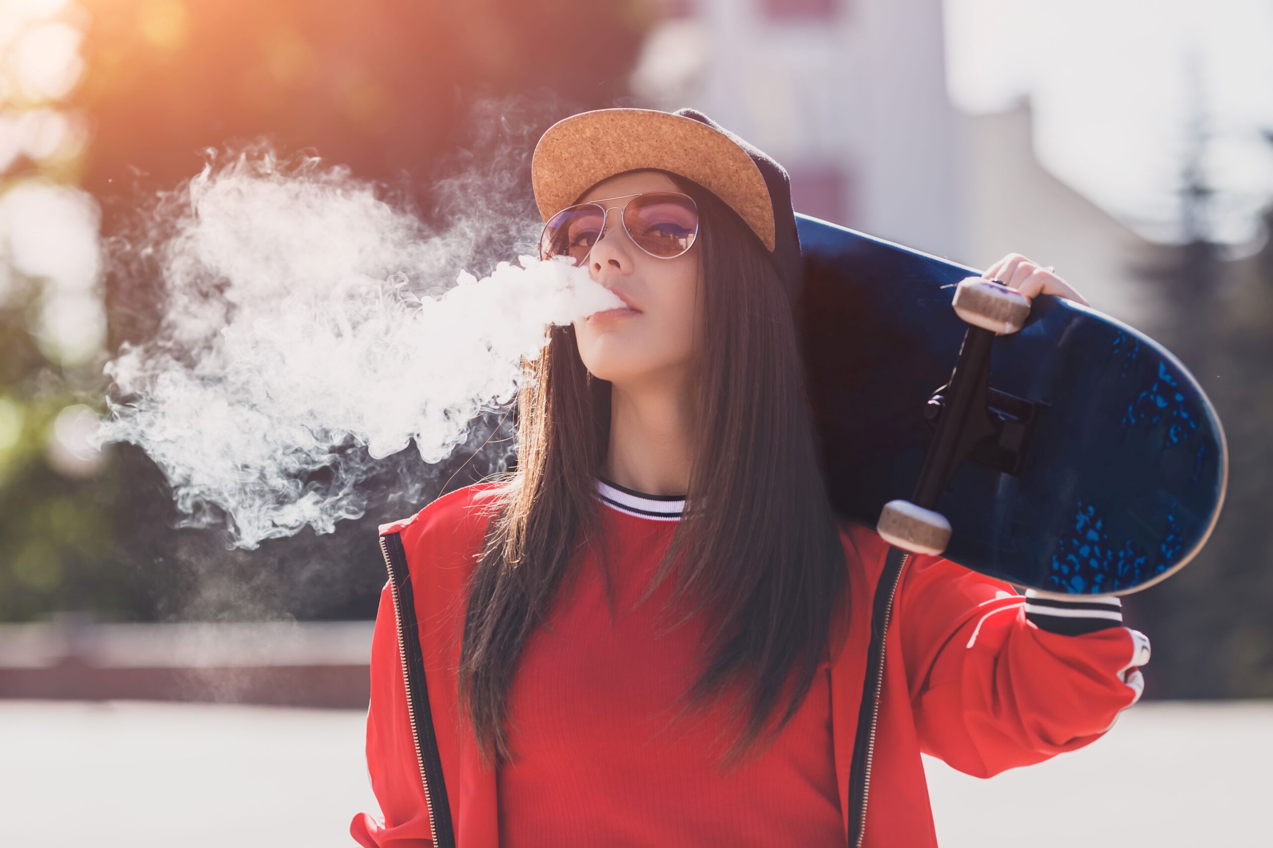 Frau mit Vape und Skateboard im Freien
